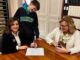 Lori Fulton Brookbank signs paperwork Tuesday to run for Maysville City Commission as her son, Ben and Mason County Clerk Stephanie Schumacher look on. Tuesday was the final day candidates could file for the 2022 election cycle.